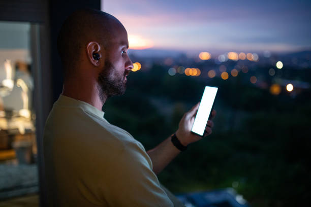 istock Male trader using mobile phone on balcony at his home during dusk hour 1412036403