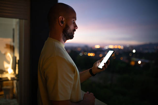 istock Male trader using mobile phone on balcony at his home during dusk hour 1412036455