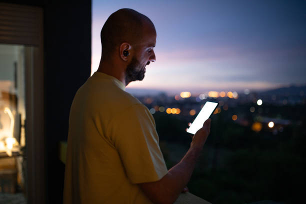 istock Male trader using mobile phone on balcony at his home during dusk hour 1412036480