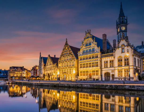 Photo of Historic medieval building illuminated after sunset on Leie river in Ghent, Belgium