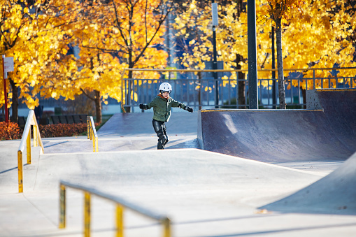 Boy skateboarding in skateboard park in autumn