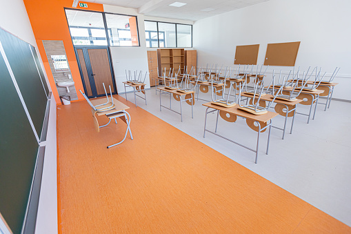 The room of the school auditorium with neatly arranged tables and chairs without people, there are no students and a teacher