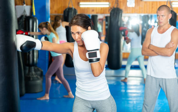 istock Asian female practicing punches with boxing bag at gym 1412044871