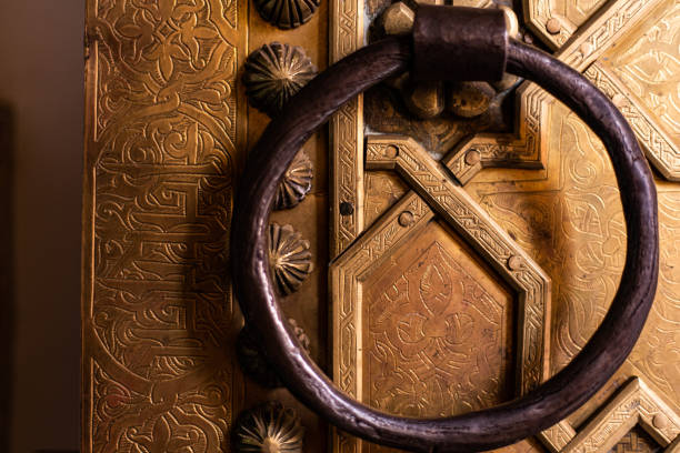 istock Golden Iron door sculpture script detail on ancient Arabian gate with iron ring 1412045921