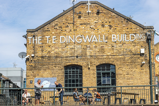 This houses a pub restaurant and is known as The TE Dingwall Building on East Yard at Camden Lock Place in Borough of Camden, London. Customers are visible.