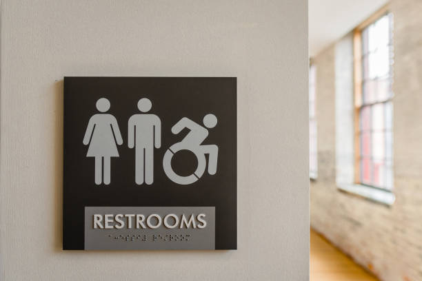 Public Toilet Sign Close-up of unisex bathroom sign against neutral colored wall with symbols for male, female, and wheelchair. Copy space. gender neutral photos stock pictures, royalty-free photos & images