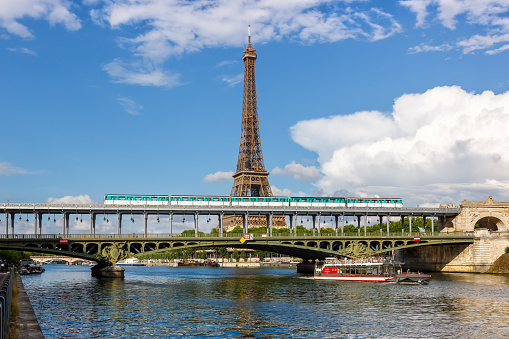 Paris, France - June 5, 2022: Metro Paris over Seine river with Eiffel tower between stations Bir-Hakeim and Passy public transport in Paris, France.