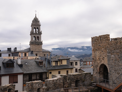 Ponferrada, Leon, Spain; 12-12-2021; The bell tower of the Basilica de la Encina de Ponferrada stands out among the buildings showing the bells, the dome and a cross on top