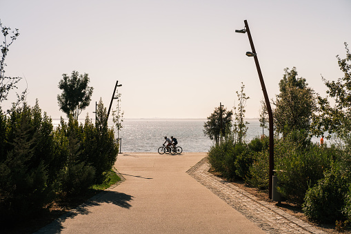 Lisboa , Portugal; 31 July 2022: two people cycling on Passeio Ribeirinho de Marvila in the morning