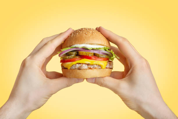 istock hamburger in hand on yellow isolated background 1412061750