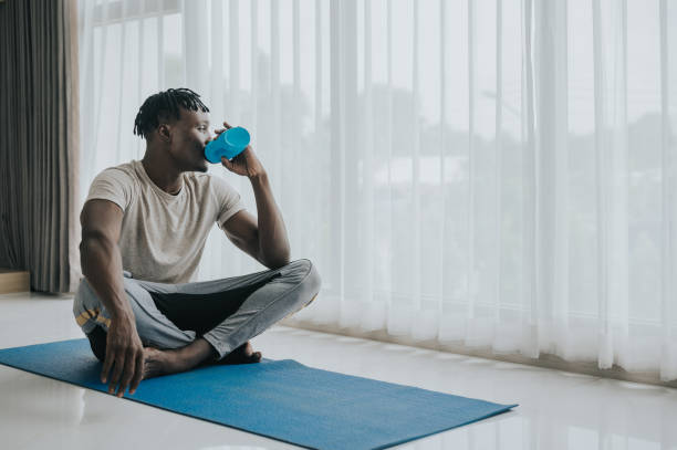 istock man drinking water after exercise at home 1412068456