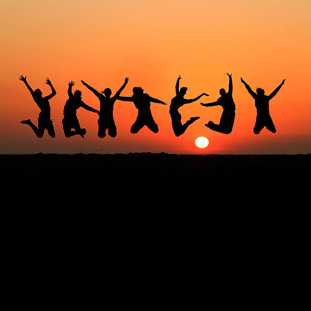 silhouette of female friends jumping in sunset stock photo