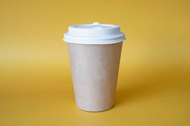 istock brown paper coffee mug on a yellow background. Empty space for text and design on a cup of coffee. The form for the name of the coffee or company or coffee shop 1412087747