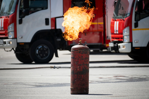 an ignited gas cylinder on the background of a fire truck on the street. Danger of explosion