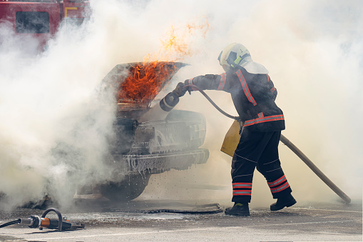 Firefighters attack a propane fire. Fireman Putting Out Fire. Firemen extinguishing a car fire.