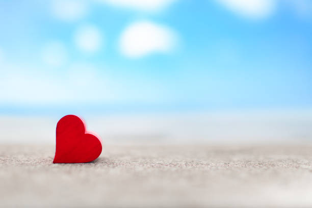 Heart on the beach against sky ocean background.