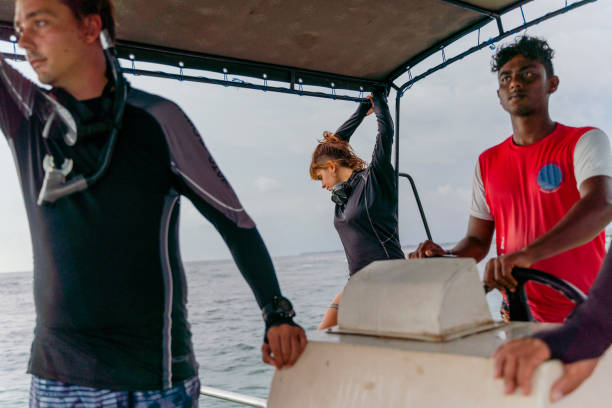 young captain, sri lankan man, control the boat with a group of divers on a way to the ocean. - men latin american and hispanic ethnicity southern european descent mature adult imagens e fotografias de stock