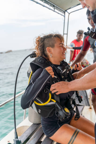 istock A man - diving instructor and personal trainer is helping to adjust diving equipment for a young happy woman aboard of a boat going to the ocean. 1412093283