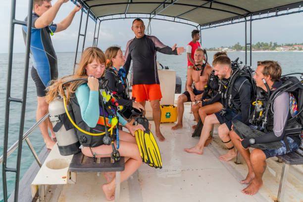 homem maduro - chefe da equipe de mergulho instruindo um grupo de mergulhadores, homens e mulheres a bordo de um barco antes de mergulhar no oceano. - men latin american and hispanic ethnicity southern european descent mature adult - fotografias e filmes do acervo