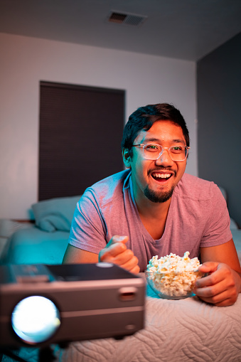 Filipino Man Watching a Movie in Bed with Projector 
Shallow DOF