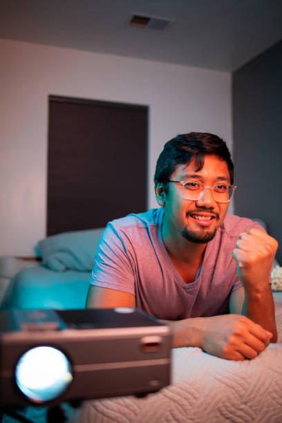 istock (Excited) Man Watching a Movie in Bed with Projector 1412119749