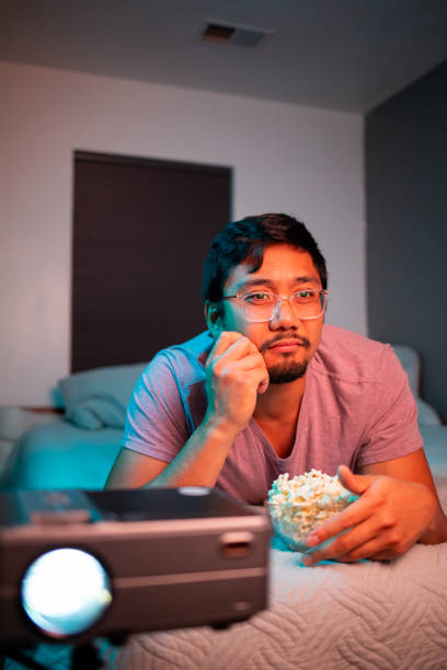 istock (Interested) Man Watching a Movie in Bed with Projector 1412119973