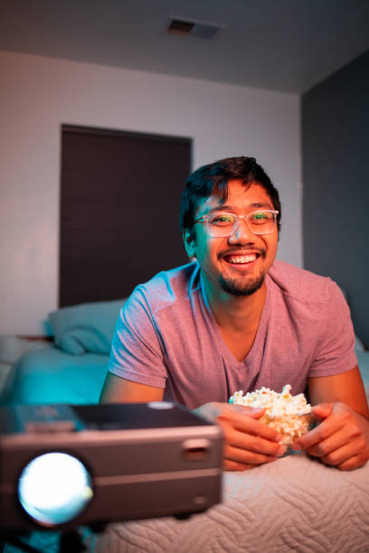 istock (Laughing) Man Watching a Movie in Bed with Projector 1412120255