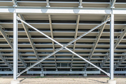 Straight on view of under stadium bleachers, steal I-Beam bleachers with X cross brace, with stone surface.
