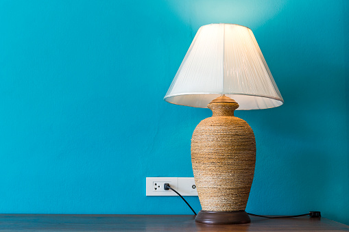 Table lamp on wooden table with space on blue wall background, interior decoration