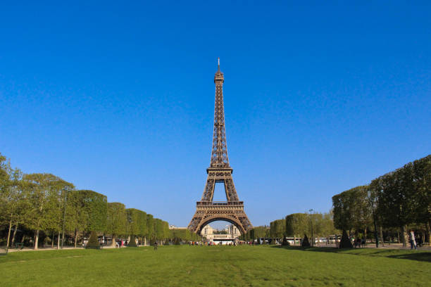 A stunning photograph of the Eiffel Tower surrounded by green gardens and a vibrant blue sky, capturing the allure and grandeur of Paris in springtime.