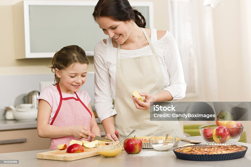 Mother and daughter cutting apples for pie Smiling mother and daughter cutting apples for baking a pie Adult Stock Photo