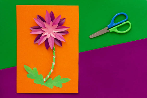 Paper flower craft by child and scissors flat lay