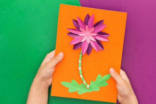 istock Paper flower craft in child hands flat lay 1412135076