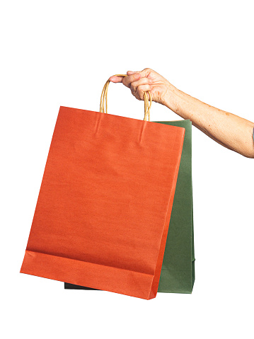 Close-up of hand senior woman holding paper bags with a white background. Space for text.