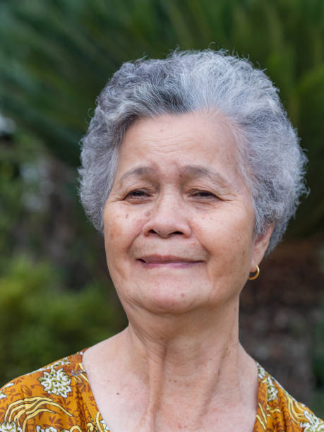 istock Senior woman smiling and looking at camera while standing in a garden 1412136319