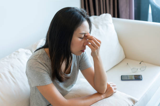 müde junge asiatische frau, die die brille abnimmt, spürt die überanstrengung der augen bei der verwendung des mobiltelefons zu hause. mädchen, das an einem syndrom des trockenen auges leidet, müdigkeit nach langem gebrauch des smartphones. - human eye rubbing tired glasses stock-fotos und bilder