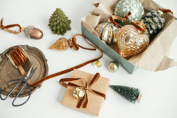 istock Stylish christmas vintage ornaments, gift, ribbon, scissors on rustic white table. Merry Christmas! Wrapping present aesthetic. Preparation for winter holidays, atmospheric time. Moody banner 1412137997