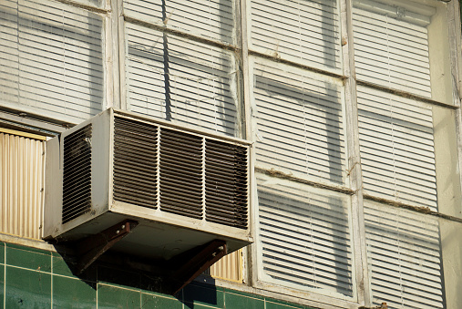 Old air conditioner in window of urban building