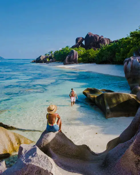 Photo of Anse Source d'Argent, La Digue Seychelles, young couple men and woman on a tropical beach during a luxury vacation in the Seychelles. Tropical beach Anse Source d'Argent, La Digue Seychelles