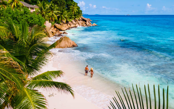 anse source d'argent, la digue seychelles, pareja joven hombres y mujeres en una playa tropical durante unas vacaciones de lujo en las seychelles. playa tropical anse source d'argent, la digue seychelles - sand summer beach vacations fotografías e imágenes de stock