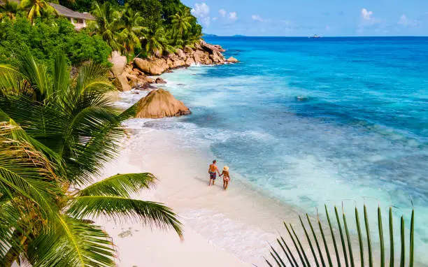 Photo of Anse Source d'Argent, La Digue Seychelles, young couple men and woman on a tropical beach during a luxury vacation in the Seychelles. Tropical beach Anse Source d'Argent, La Digue Seychelles