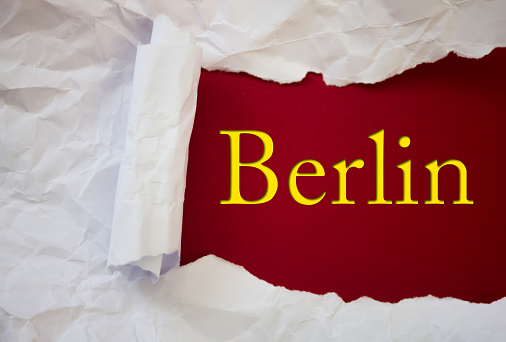 Berlin text with Torn, Crumpled White Paper on colored background.