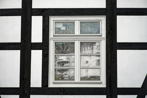 closeup of windows with Wall of old german half-timbered house with black wooden beams and white plaster form the street