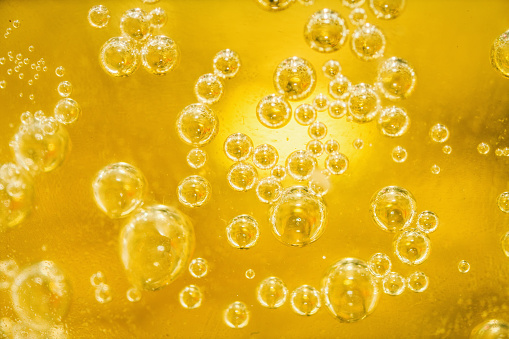 Many water bubbles on shaded golden surface float together. Golden background template with round particles