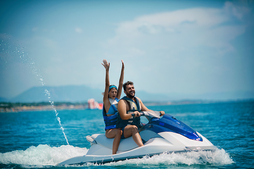 Young couple jet skiing. They are smiling and enjoying summer sport on water.