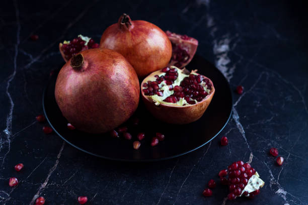 istock Pomegranate fruits on the black plate on the marble table. 1412148800