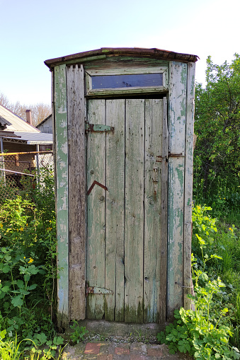 Old rustic wooden toilet in a countryside in summer, vertical photo