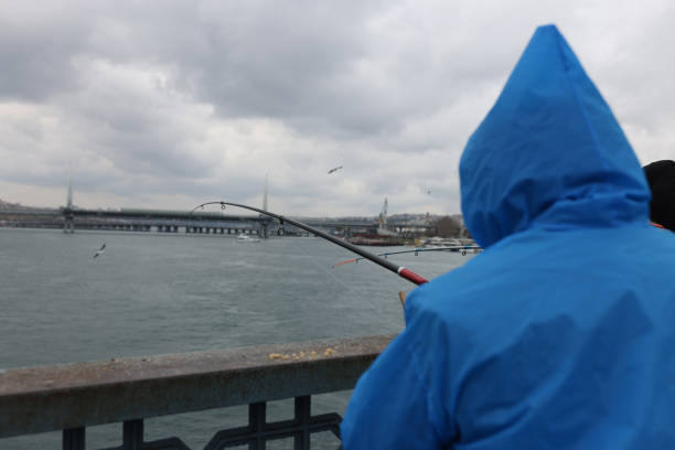 istock Fisherman in blue cloak stands with back and catches fish with bait 1412153069