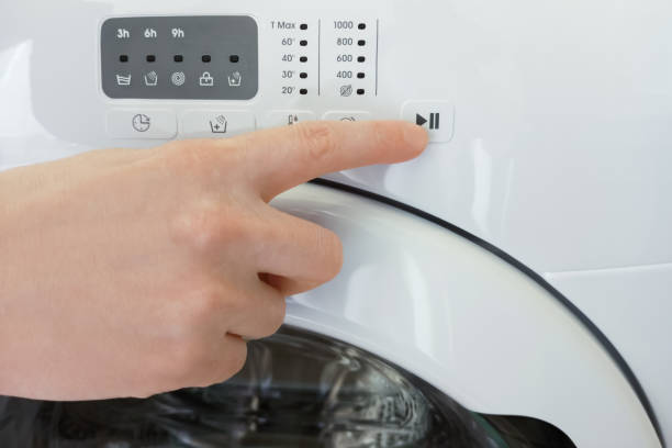istock Presses the start button with his finger on  washing machine close-up. 1412153995