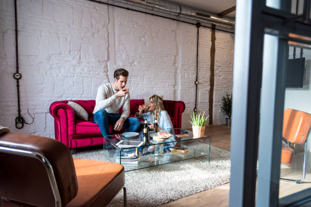 istock happy couple eating a pizza on the couch 1412157471